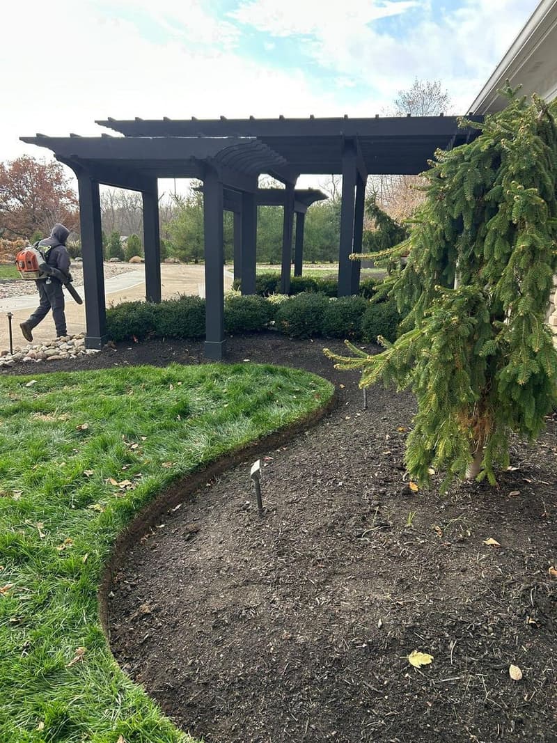 Curved mulch bed edging beside pergola and lawn