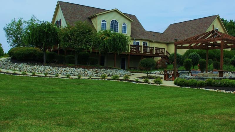 Large yellow house with rock garden and lawn