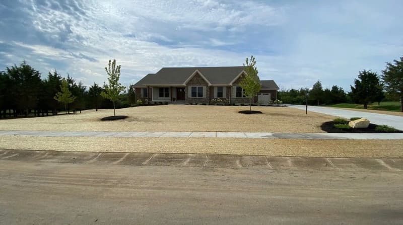 Graded gravel yard with young trees at new home
